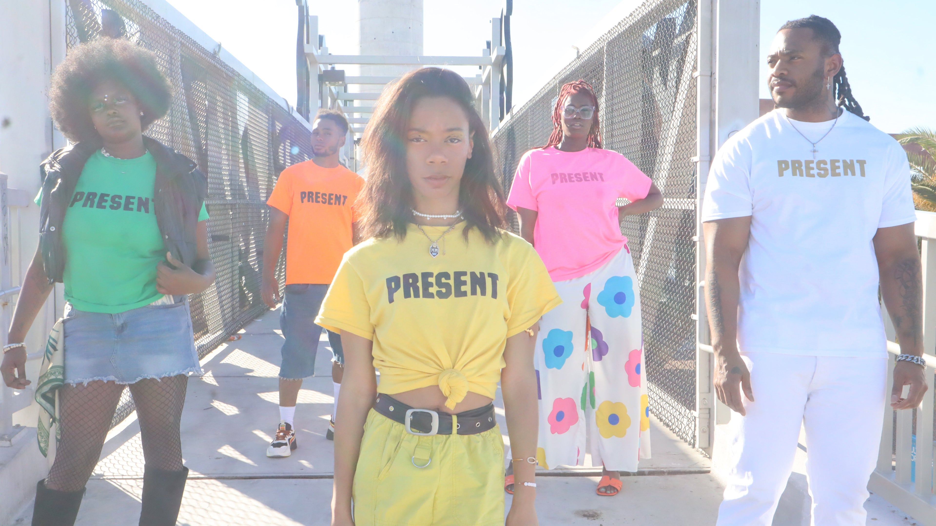 Group of people wearing 'PRESENT' t-shirts on a bridge